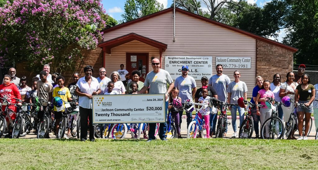 a group of kids with new bikes, smiling and a big check for 20k held by GTP employees