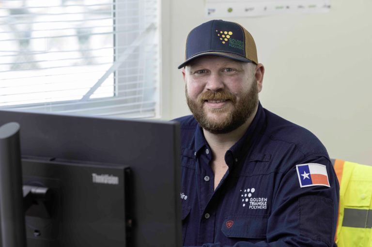 A man in a GTP hat and uniform sitting at a desk looking at the camera smiling
